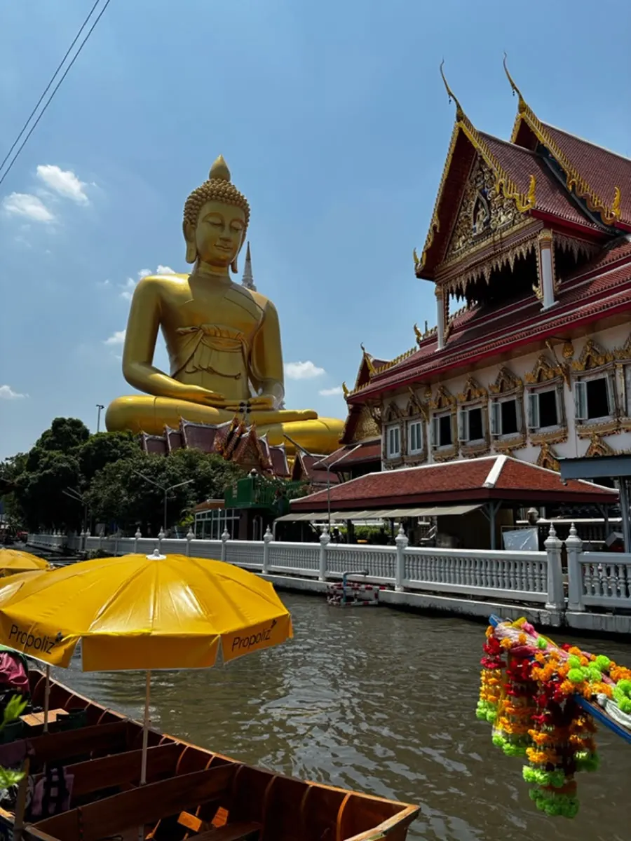 Canal with boats and a golden Buddha in Bangkok